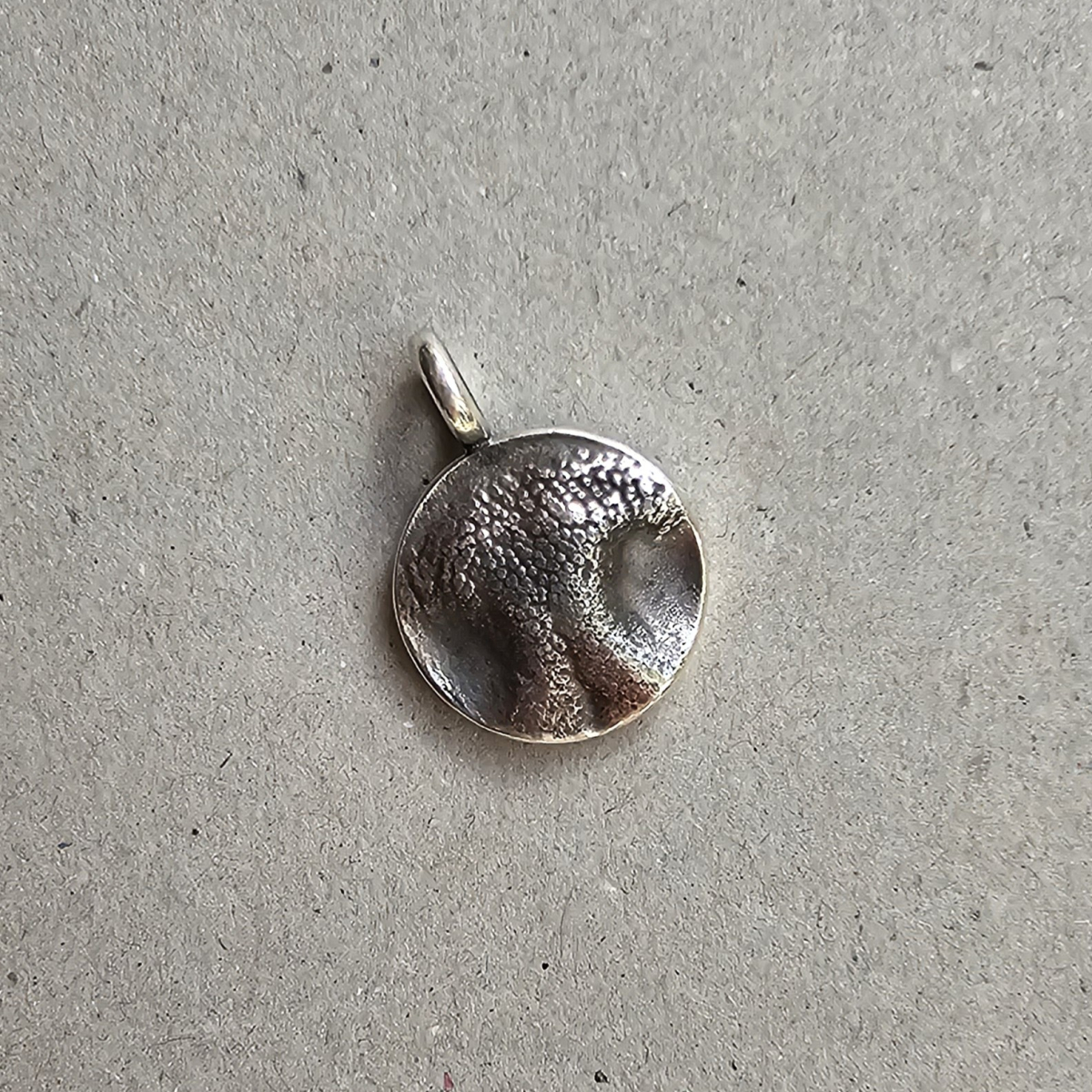 Nahaufnahme des puren, runden Hundenasen-Anhängers aus echtem Silber aus der eigenen Werkstatt, der das naturgetreue Relief des Nasenabdrucks ganz ohne Schlüsselring oder Lederband zeigt.