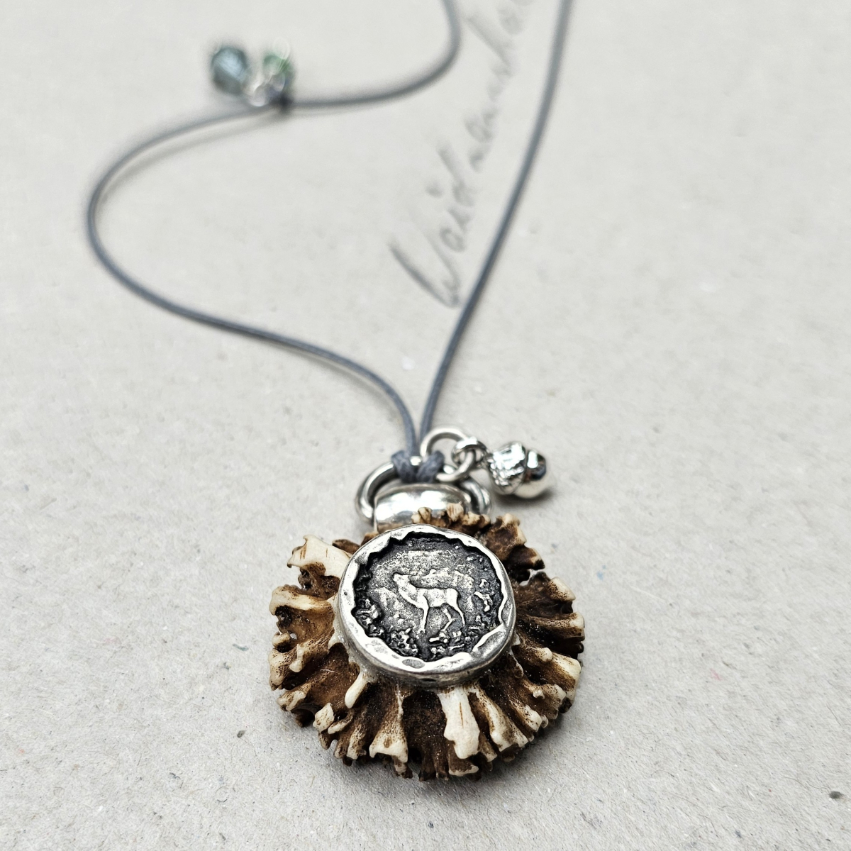 Trachtenkette aus echter Rehrose mit versilberter Motivplatte eines Hirsches und zwei funkelnden Swarovski Kristallen an einem graublauen, gewachsten Baumwollband.