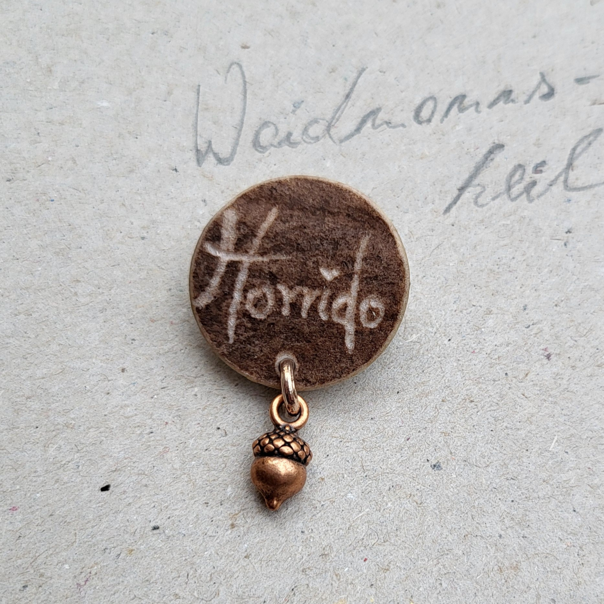 Handgefertigte Jagdbrosche aus Hirschhorn mit Horrido Schriftzug und bronzefarbenem Eichel Anhänger